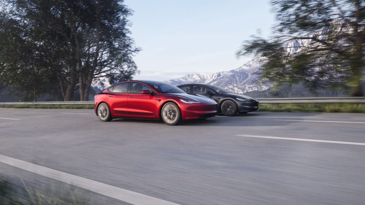 Red and black 2025 Tesla Model 3 electric sedans driving side by side on a highway with mountain scenery
